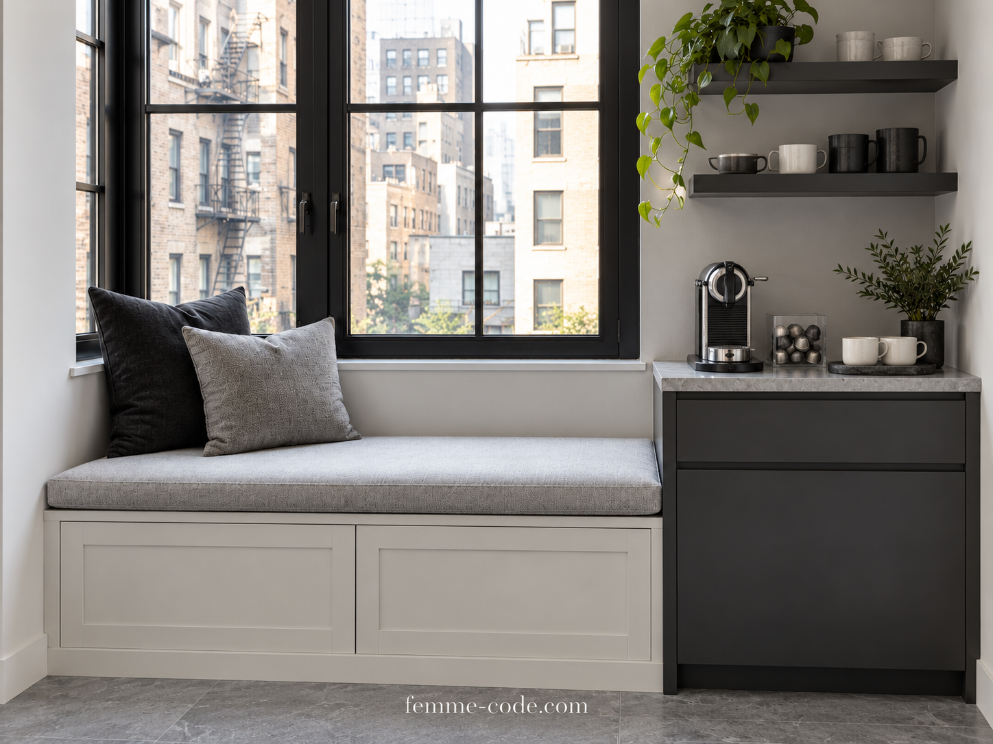Off-white storage bench beneath a tall black-framed window beside an anthracite coffee cabinet with a capsule machine, capsule holder and ivory cups.